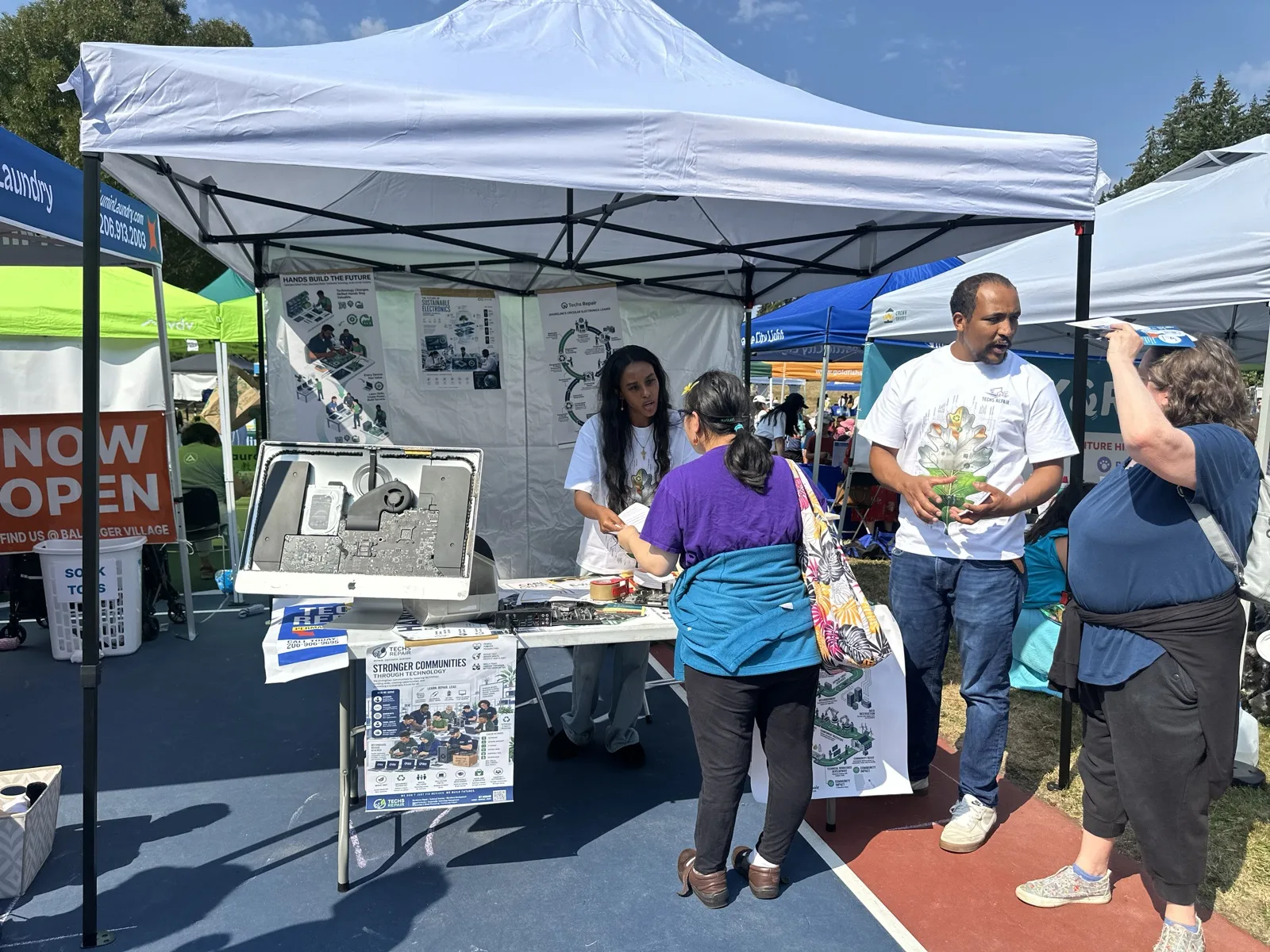 Techs Repair outreach booth with staff and visitors at a community event
