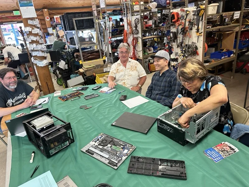 Hands-on electronics repair workshop with participants working on disassembled desktop computers